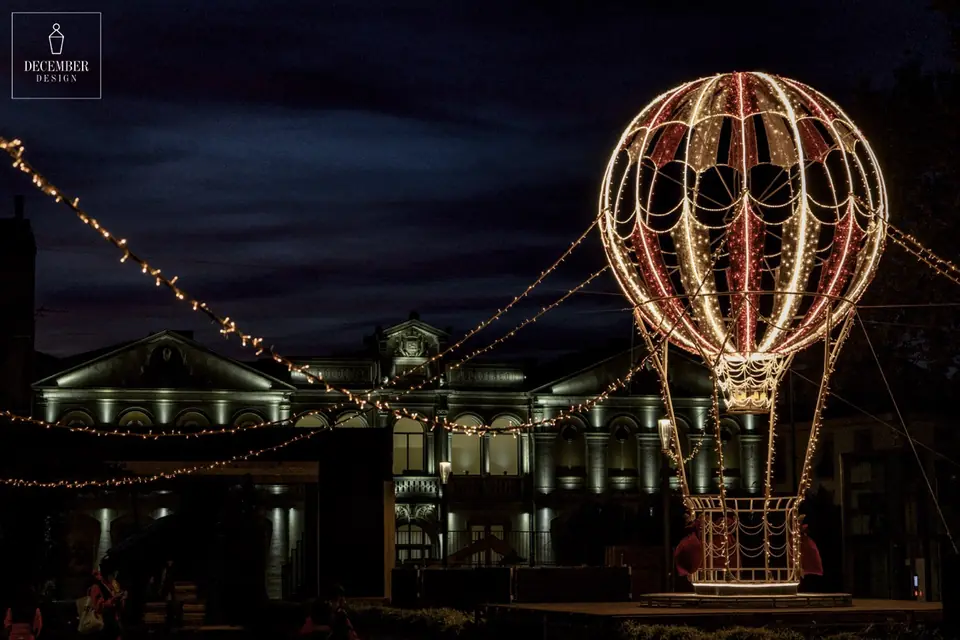 Light balloon at night against the facade of the theater building, strings of lights stretched above it