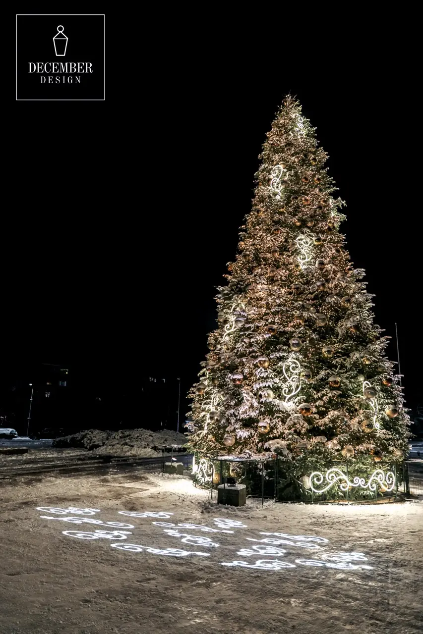 A tall, warm white illuminated Christmas tree with golden balls and circular light elements in the snow