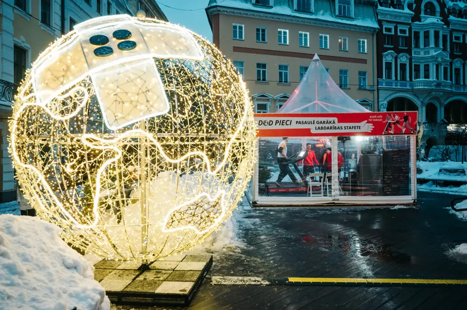 An illuminated globe with a symbolic patch near the tents of the charity relay running track