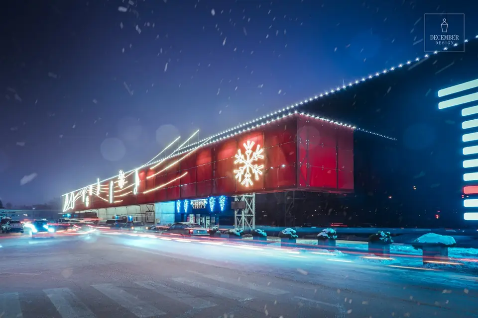 Red facade of Bruklinas shopping centre with snowflake decorations on a snowy evening