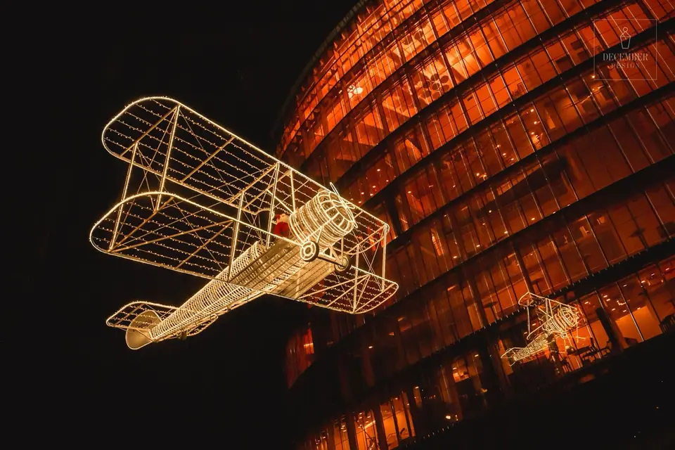 A light plane hangs on a glass facade of a city at night