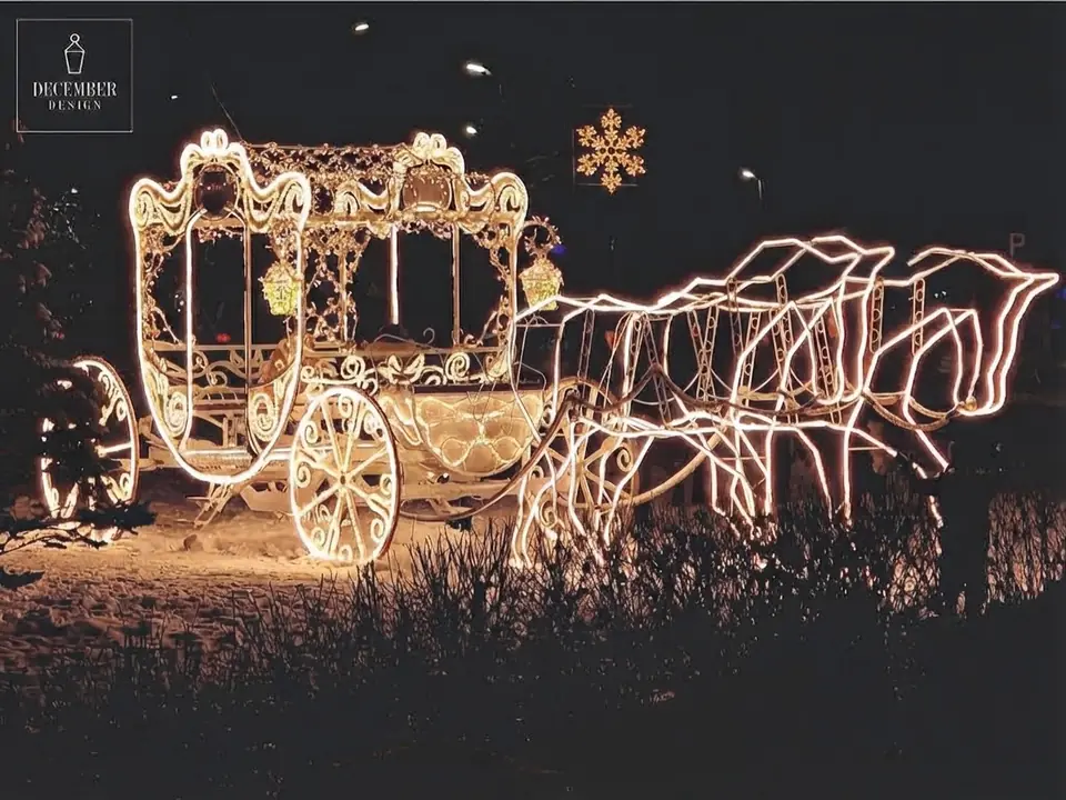 Light sculpture - a carriage drawn by three horses, all outlined in bright lines of light in the snow at night