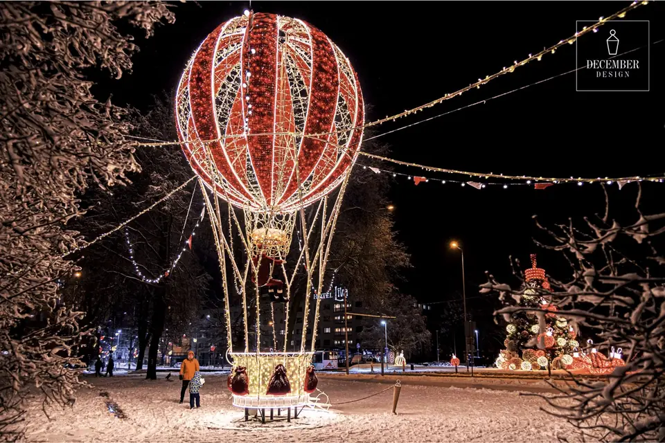 A light balloon with Santa Claus in a basket, a child is looking at it - Hotel Līva can be seen in the background