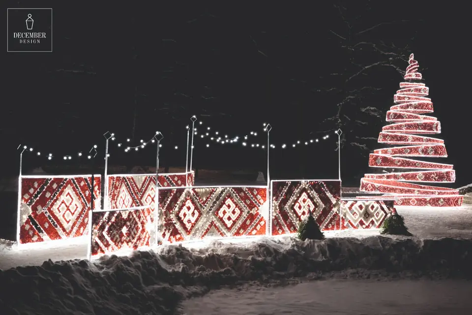 Red and white spiral fir tree and light panels with Latvian characters at night in the snow