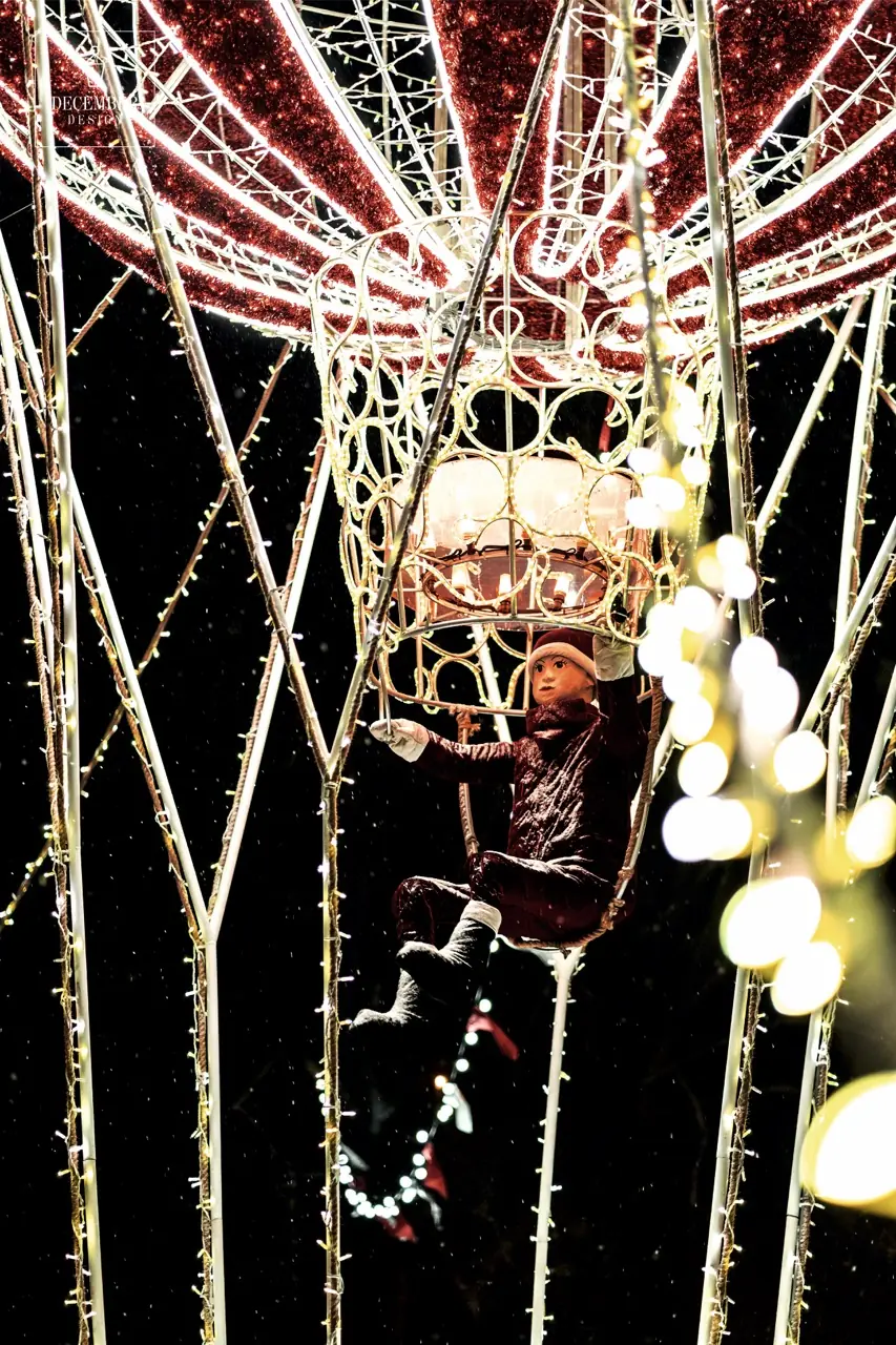 Close-up of Christmas elf in balloon ropes, decorated with red shiny fabric and lights
