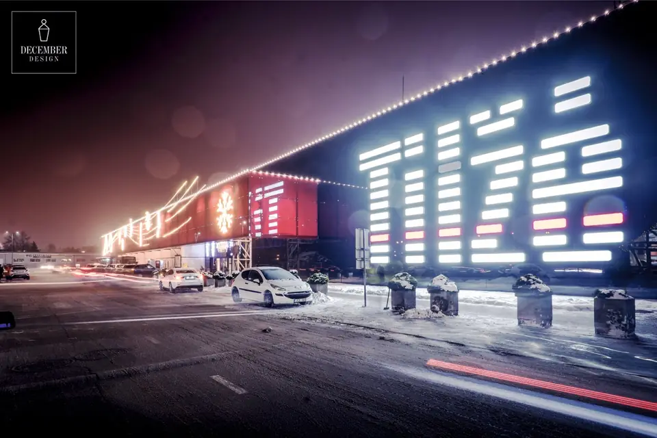 Tilžė shopping centre facade at night - light strings along the roof line, snowflakes and a grid of light panels