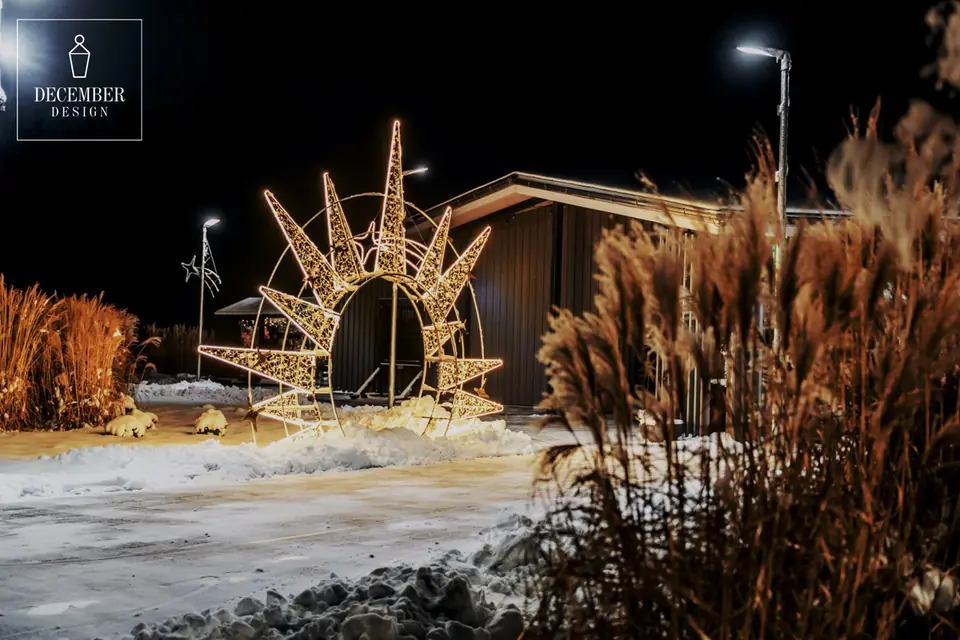 Sun-shaped light arch in the snow near the building at night