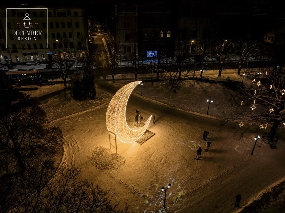 A bird's eye view of the light moon sculpture - people are walking around it in a snowy square