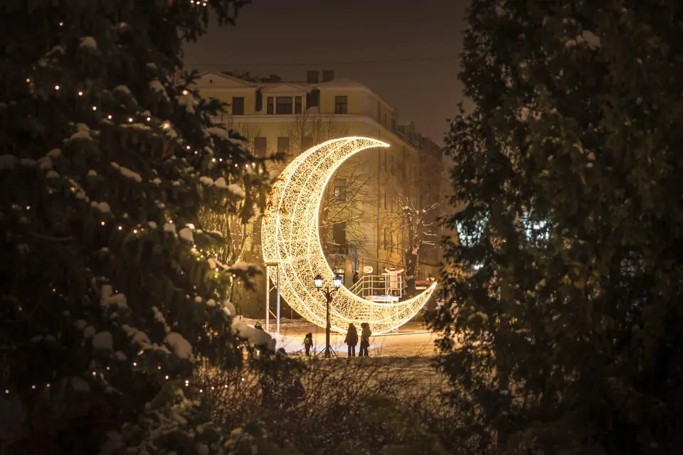 Illuminated moon sculpture in a snowy park — December Design urban installation