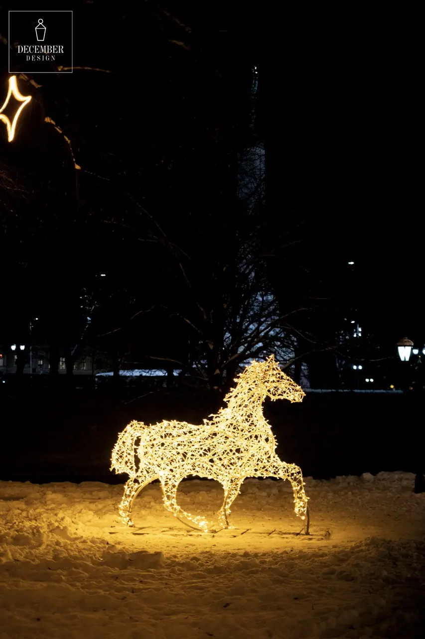 Light horse sculpture in the park at night - a warm glow on the background of snow