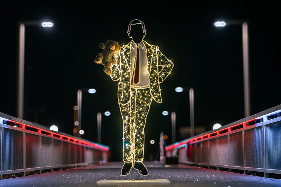 Light figure sculpture on a city street at night