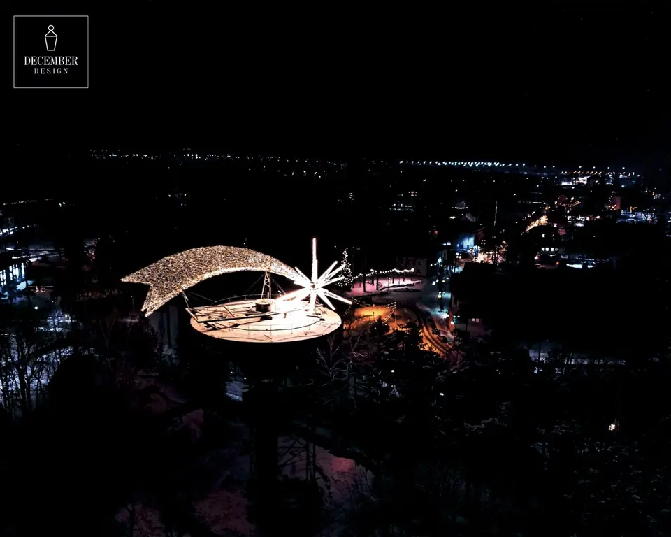 Light star on the top of the tower above the illuminated city at night, aerial view