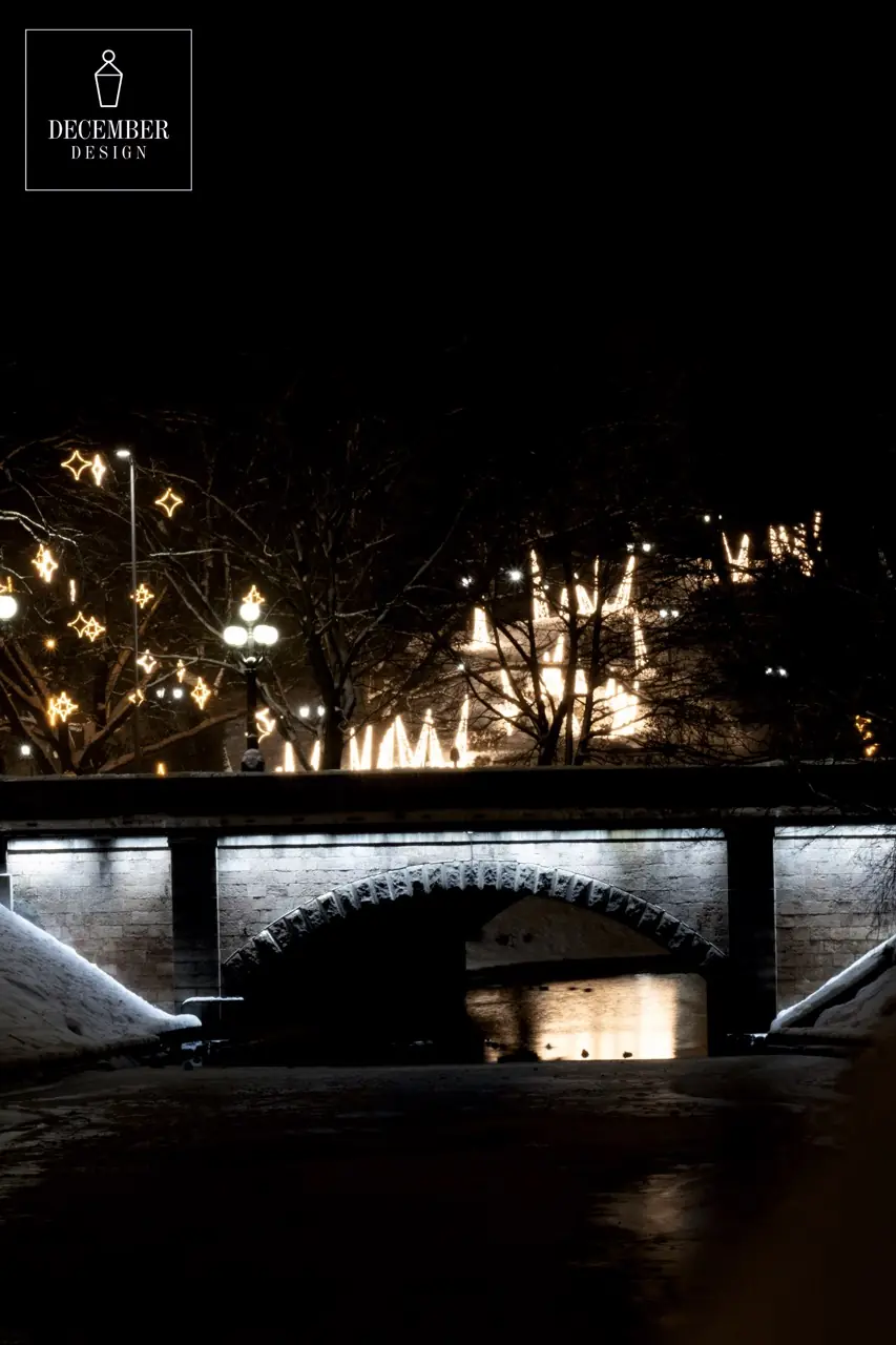 A bridge over a city canal at night - a white arc of light reflected in dark water