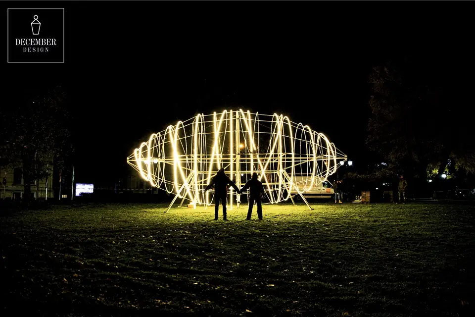 Two people holding hands against a glowing light airship at night