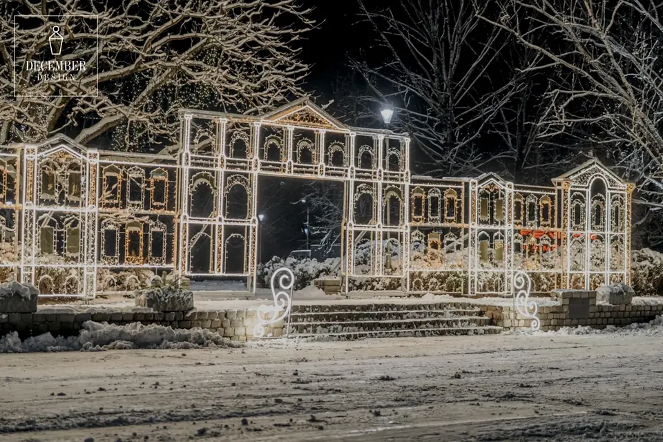 Light installation of a classic building facade with arches and circular plinths in a snowy park